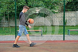 Outdoor portrait of teenage boy playing street basketball, copy space