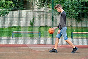 Outdoor portrait of teenage boy playing street basketball, copy space