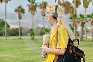 Outdoor portrait of teenage female student in headphones with laptop backpack