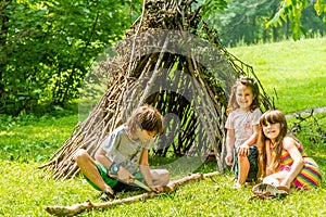 Outdoor portrait of three happy kids - boy and girls - playing n