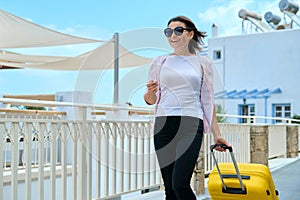 Outdoor portrait of tourist woman with suitcase at hotel sea spa resort, copy space