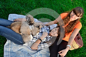 Outdoor portrait of two cute girls hugging with ginger cat and puppy of Chinese Shar Pei dog on green grass. Ywo happy smiling che