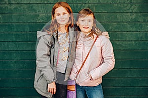 Outdoor portrait of two cute little teen girls wearing warm jackets