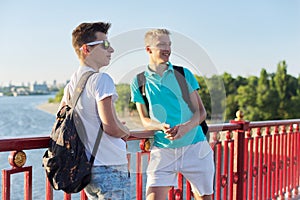 Outdoor portrait of two friends boys teenagers 15, 16 years old, talking laughing