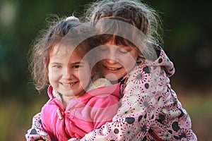 Outdoor portrait of two young happy children, girls - sisters -
