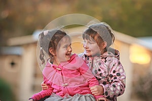 Outdoor portrait of two young happy children, girls - sisters -