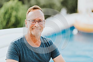 Outdoor portrait of 50 year old man resting by the pool