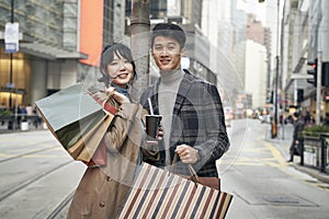 Outdoor portrait of young asian couple holding shopping bags