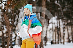 Outdoor portrait of young attractive woman with bagpack posing in the park. Model wearing stylish warm clothes. City