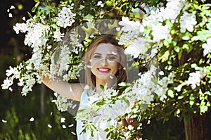 Outdoor portrait of young attractive woman in garden of blooming apple trees. Woman's Day. Female spring concept.