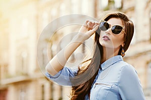 Outdoor portrait of a young beautiful confident woman posing on the street. Model wearing stylish sunglasses. Girl