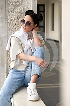 Outdoor portrait of a young beautiful confident woman posing on the street. Model wearing stylish sunglasses. Girl