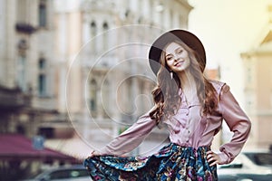 Outdoor portrait of a young beautiful fashionable happy lady posing on the street. Model wearing stylish clothes. Girl