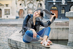 Outdoor portrait of young beautiful fashionable mixed raced Asian lady posing on the background of old morning city