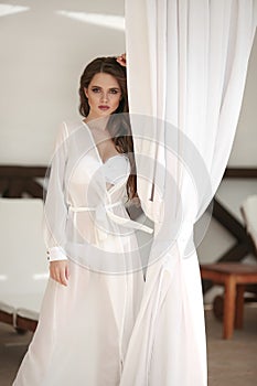 Outdoor portrait of young beautiful girl. Ð¡arefree brunette wearing in chiffon Wear dress by white curtain on beach lounge