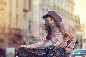 Outdoor portrait of young beautiful happy lady posing on street. Model wearing stylish clothes. Girl looking down. Sunny