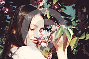 Outdoor portrait of young beautiful happy smiling lady posing near flowering tree.