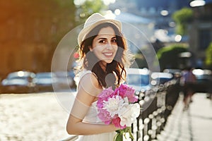 Outdoor portrait of young beautiful happy smiling lady posing on the street. Model wearing stylish white clothes and