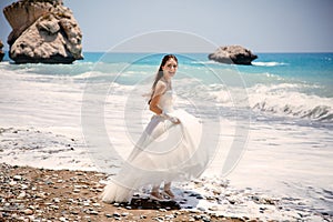 Outdoor portrait of young beautiful woman bride in wedding dress on beach. Petra tou Romiou - Aphrodite's Rock.