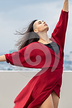 Outdoor portrait of young beautiful woman dancing on the rooftop