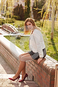 Outdoor portrait of young beautiful woman posing on street in sunny day. Female fashion. City lifestyle.