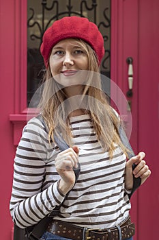 Outdoor portrait of young beautiful woman in striped shirt and red beret. A lady is dressed in the French style.