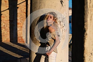 Outdoor portrait of a young blonde woman on city street. Sexy woman walking outdoors. Sensual girl posing on street