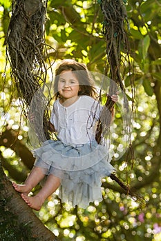 Outdoor portrait of young child girl in magic forest, swinging o