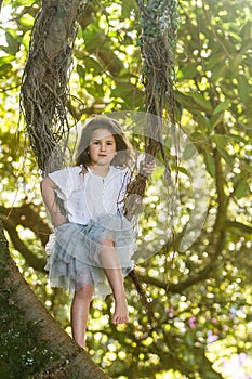 Outdoor portrait of young child girl in magic forest, swinging o