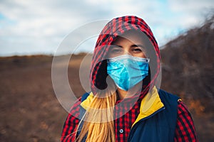 Outdoor portrait of young girl with medical face mask against viruses. Prevention of coronavirus and covid-19.