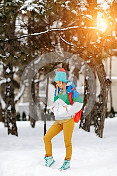 Outdoor portrait of young handsome girl with bagpack posing in the park. Model wearing stylish warm clothes. City