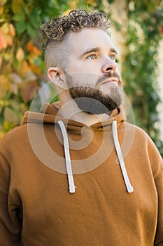 Outdoor portrait of young handsome smiling curly hair style man with beard in spring season