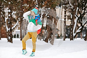 Outdoor portrait of young handsome smiling girl with bagpack posing in the park. Model wearing stylish warm clothes