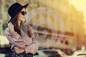 Outdoor portrait of young happy lady posing on street. Model wearing stylish clothes. Girl looking aside. Sunny day