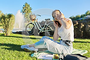 Outdoor portrait of young happy woman in headphones, listening to music