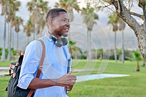 Outdoor portrait of young man with laptop headphones and backpack