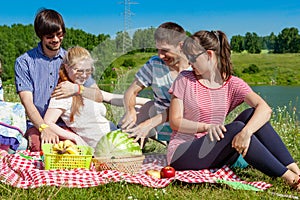 Outdoor portrait of young people having a picnic, eat watermelon