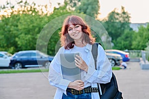 Outdoor portrait of young female college student with backpack, laptop