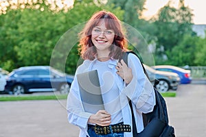 Outdoor portrait of young female college student with backpack, laptop