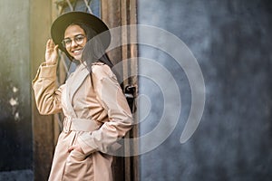 Outdoor portrait of young stylish woman wearing trendy fall outfit , black hat standing on the street