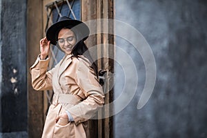 Outdoor portrait of young stylish woman wearing trendy fall outfit , black hat standing on the street