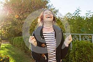 Outdoor portrait of a young teen girl with an emotion of happiness, success, victory,golden hour