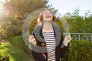 Outdoor portrait of a young teen girl with an emotion of happiness, success, victory,golden hour photo