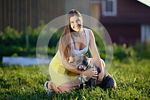 Outdoor portrait of young white female with an American Bullie who sticks her tongue out, European female cuddling her