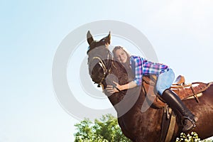 Outdoor portrait of young woman hugging her horse