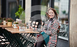 Outdoor portrait of young woman is sitting in street cafe