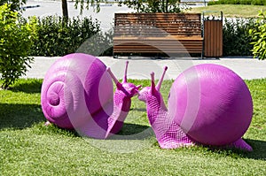Outdoor recreation place in the park. Two sculptures of purple snails on a green grass lawn.