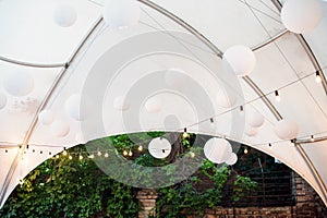 Outdoor restaurant dome with party decorations. Paper lanterns and light garlands. Wedding decor, summer restaurant outroors