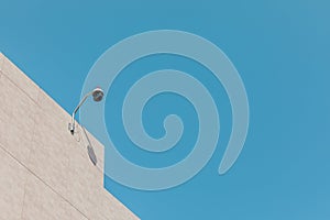 Outdoor round CCTV camera on roof of building against blue sky