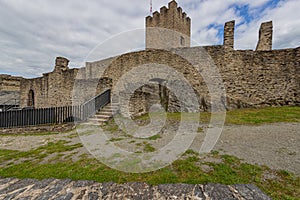 Outdoor ruins of medieval Bourscheid castle, weathered stone walls, staircase, metal railing and tower